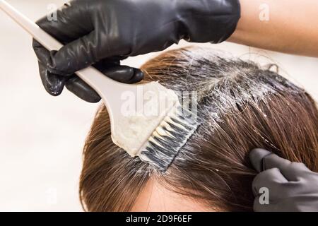 Gros plan de la coiffeuse appliquant un colorant chimique sur les cheveux Banque D'Images