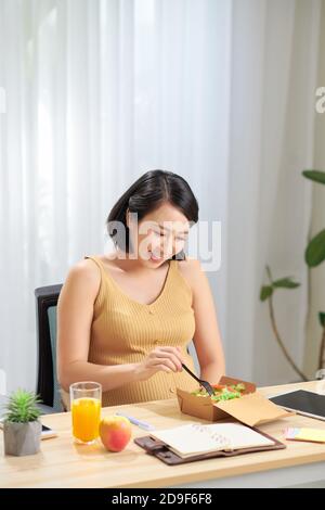 Jeune femme enceinte utilisant un comprimé numérique manger de la salade fraîche et fruits sur table Banque D'Images