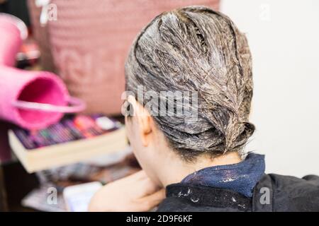 Gros plan de la coiffeuse appliquant un colorant chimique sur les cheveux Banque D'Images