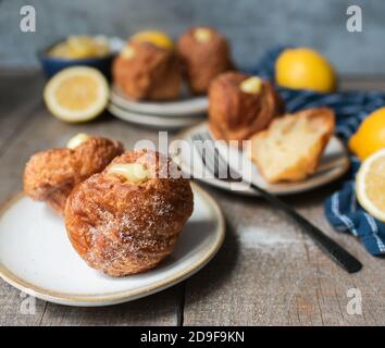 Cruffins au citron sur une table en bois avec assiettes et fourchettes. Banque D'Images