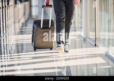 Vue sur la terre de homme passager dans élégant vêtements formels est dans le hall de l'aéroport à pied avec les bagages Banque D'Images