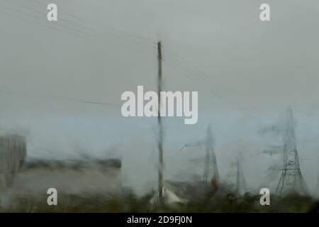 Une sombre scène balayée par le vent de Dungeness Power-station à Kent, Royaume-Uni. Photographié à travers un pare-brise de voiture mouillé comme la pluie a versé. Banque D'Images