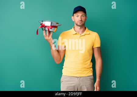 liveur dans un bouchon tenant une casserole avec un ruban sur le bleu Banque D'Images