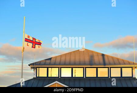 Le drapeau RNLI survolant le centre du canot de sauvetage au coucher du soleil À Fleetwood Banque D'Images