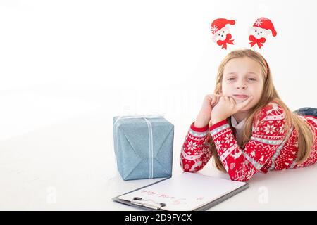 Petite fille réfléchie écrit la lettre au Père Noël sur fond blanc.objectifs plans rêves faire pour faire la liste pour le nouveau concept de noël d'année. Spécial Banque D'Images