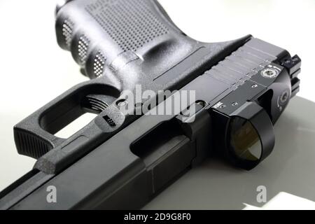 Gros plan d'un pistolet de 9 mm sur fond blanc. Pistolet avec un point de vue rouge. Glolock 19. Banque D'Images