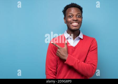 Homme afro-américain souriant pointant de côté sur l'espace réservé aux copies Banque D'Images