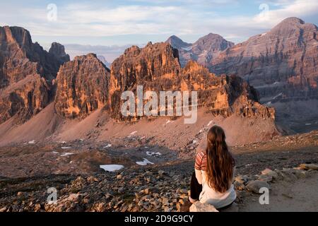 une fille regardant le coucher du soleil dans les dolomites faire les montagnes brillent Banque D'Images