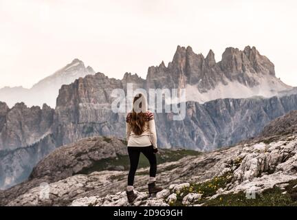 une fille regardant le coucher du soleil dans les dolomites faire les montagnes brillent Banque D'Images