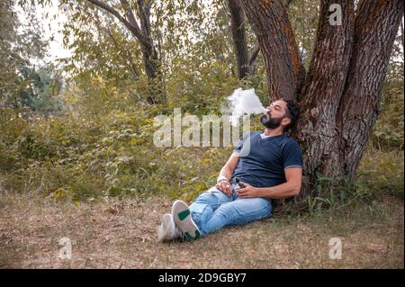 Un beau homme de vape souffle un couple une cigarette électronique. Des façons modernes de cesser de fumer. Banque D'Images