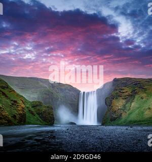 Célèbre cascade de Skogafoss sur la rivière Skoga au coucher du soleil. Islande, Europe. Grand ciel violet brillant sur fond. Photographie de paysage Banque D'Images