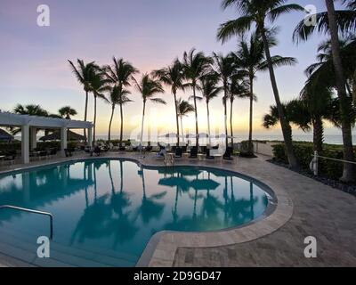 Naples, FL/USA - 10/30/20: Coucher de soleil sur le golfe du Mexique avec chaises longues et palmiers dans un club de plage privé tropical à Naples, Floride Banque D'Images