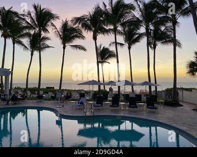 Naples, FL/USA - 10/30/20: Coucher de soleil sur le golfe du Mexique avec chaises longues et palmiers dans un club de plage privé tropical à Naples, Floride Banque D'Images