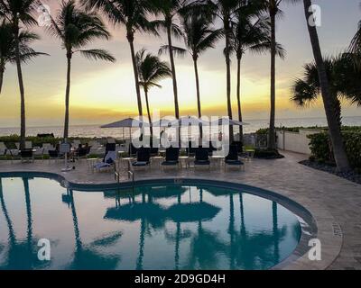 Naples, FL/USA - 10/30/20: Coucher de soleil sur le golfe du Mexique avec chaises longues et palmiers dans un club de plage privé tropical à Naples, Floride Banque D'Images