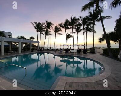 Naples, FL/USA - 10/30/20: Coucher de soleil sur le golfe du Mexique avec chaises longues et palmiers dans un club de plage privé tropical à Naples, Floride Banque D'Images