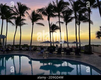 Naples, FL/USA - 10/30/20: Coucher de soleil sur le golfe du Mexique avec chaises longues et palmiers dans un club de plage privé tropical à Naples, Floride Banque D'Images