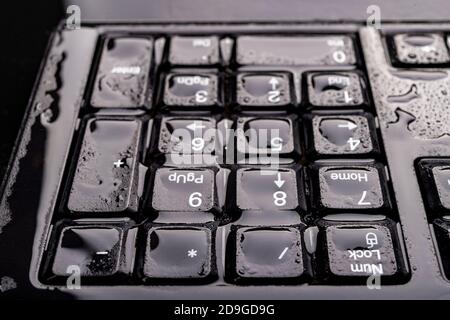 Gouttes d'eau sur le clavier de l'ordinateur. Touches d'ordinateur inondées d'eau. Arrière-plan sombre. Banque D'Images