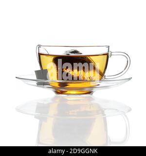 Thé dans une tasse en verre avec soucoupe sur blanc avec reflet Banque D'Images