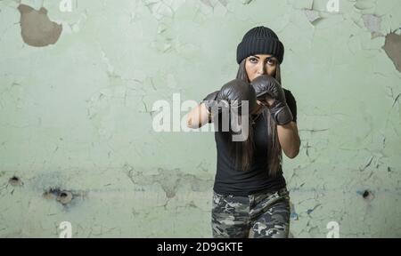 Jeune fille boxer entraînement dans des gants pour les arts martiaux mixtes dans l'ancienne salle de sport intérieure Banque D'Images