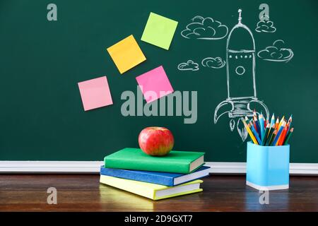 Livres et articles de papeterie près du tableau noir en classe Banque D'Images