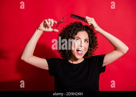 Portrait de la belle femme adorable professionnelle styliste tenir la brosse de ciseaux couper les cheveux isolés sur fond rouge Banque D'Images