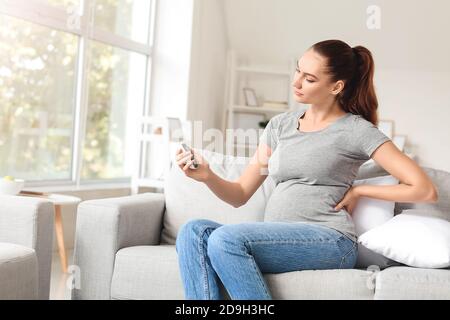 Femme enceinte diabétique mesurant le taux de sucre dans le sang à la maison Banque D'Images