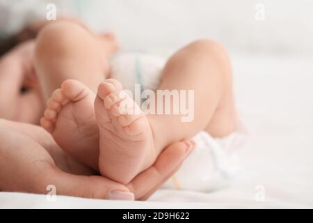 Main de la mère tenant les petites jambes de son bébé, gros plan Banque D'Images