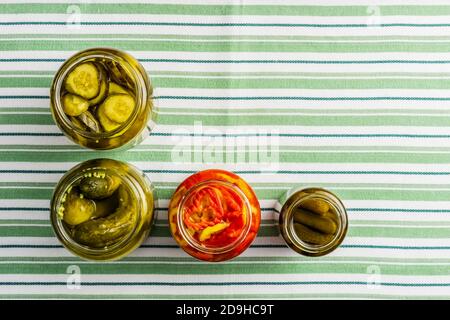 ouvert des pots avec des concombres marinés et du poivre sur fond de tissu rayé. Banque D'Images