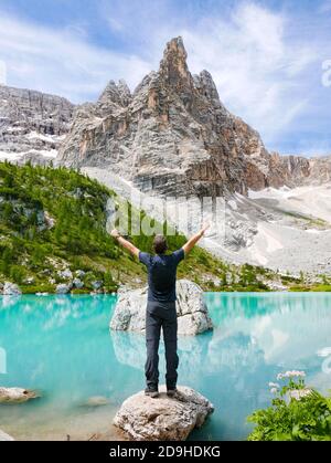 Homme aux poings dans l'air devant la belle vue de la montagne Sorapiss, Italie Banque D'Images