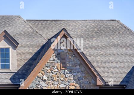 Double pignon avec parement de placage en pierre sombre, avec des sommets en forme de triangle, sur un grenier de toit incliné dans un quartier américain de maison unifamiliale, USA, dou Banque D'Images