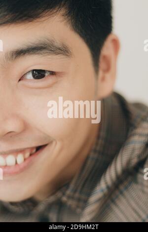 Gros plan vertical demi-visage portrait d'un asiatique mignon amical homme souriant avec joie Banque D'Images