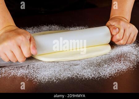 Chef utilisant un rouleau sur blanc fondant. Faire la décoration de gâteau. Banque D'Images