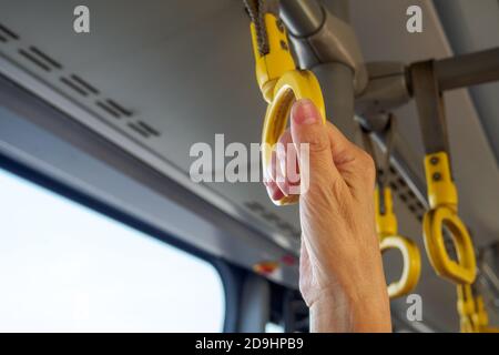 Vue rapprochée de la main tenant la poignée jaune dans les transports en commun. Copier l'espace pour le texte Banque D'Images