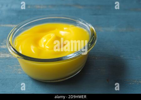 Délicieux citron caillé dans un bol en verre fond en bois bleu Banque D'Images