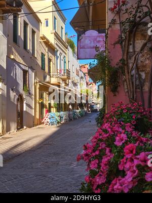 Belle vue sur les rues étroites de la vieille ville de Chania, Crète, Grèce en début de matinée. Cafés et restaurants de la rue. Mise au point sélective. pétunia rose. Banque D'Images