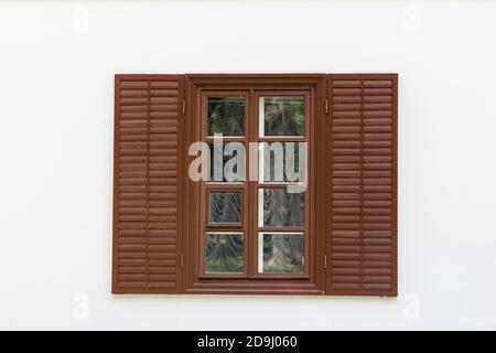 Fenêtre avec volets en bois marron et mur blanc Banque D'Images