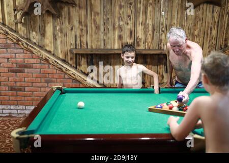 Grand-père avec ses deux petits-fils jouant au billard à la maison