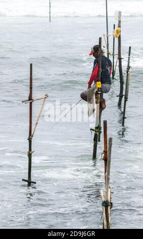 Pêcheur de stilt avec sa tige en bois face côté avec sa poche sur le poteau pour remplir avec du poisson, la pêche dans une méthode unique traditionnelle dans le Sri Lankan cu Banque D'Images