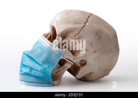 Propagation de la peur pandémique, de l'épidémie de grippe infectieuse et de la maladie contagieuse concept avec crâne portant un masque chirurgical bleu isolé sur le backgro blanc Banque D'Images