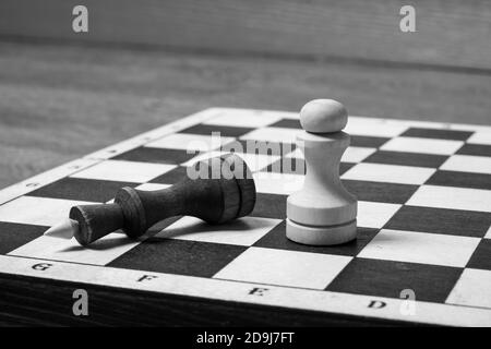 À la fin du jeu d'échecs, le pion blanc a vaincu le roi noir. Le roi déchu des échecs comme métaphore de la chute du pouvoir. Espace de copie de concept d'entreprise, mise au point sélective, noir et blanc Banque D'Images