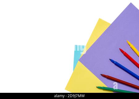 Crayons, feutres de couleurs arc-en-ciel sur feuilles de papier lilas bleu et jaune isolées sur fond blanc. Concept de retour à l'école, dessin. Minimalisme, pose à plat, espace de copie, vue de dessus Banque D'Images