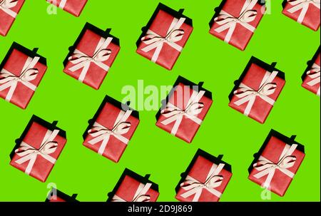 Motif de Noël - un motif d'une boîte rouge attachée avec un ruban blanc sur fond vert clair Banque D'Images