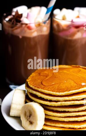 Crêpes, flappes, pancakes, griddleckes aux morceaux de banane, sirop d'érable et beurre. Petit déjeuner de Noël Banque D'Images