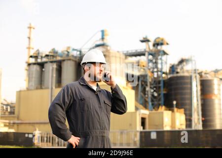 Travailleur industriel parlant par walkie portatif VHF près de l'usine à l'extérieur. Banque D'Images