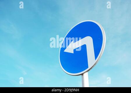 Panneau de signalisation bleu indiquant un virage à gauche. Banque D'Images