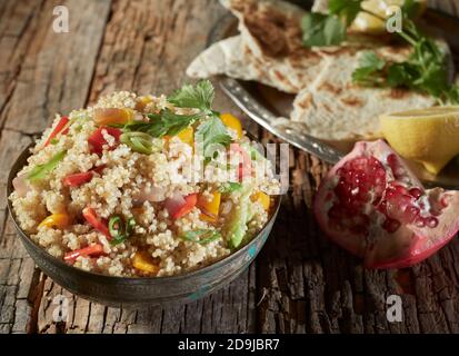 Salade de couscous et de quinoa avec grenade et doux coloré poivrons sur une table rustique en bois, vue en grand angle Banque D'Images