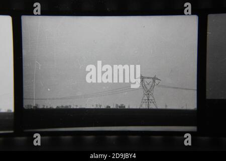 Belle photographie en noir et blanc vintage des années 1970 du brouillard et des lignes électriques vues sur la route lors d'un trajet matinal dans le pays. Banque D'Images