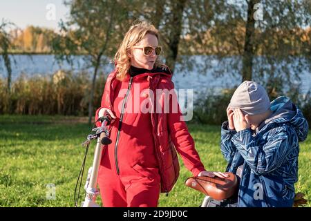 Mère dans le parc d'automne et l'enseignement à son fils de faire du vélo. Le concept d'élever une personne saine Banque D'Images