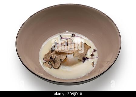 Œuf cuit avec une truffe en tranches dans une assiette en faïence, isolée sur blanc Banque D'Images