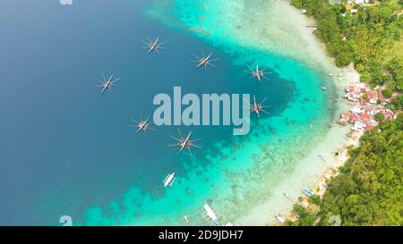 Drone aérien de village de pêcheurs avec maisons et bateaux de pêche. Île de Samal, Philippines, Mindanao. Banque D'Images
